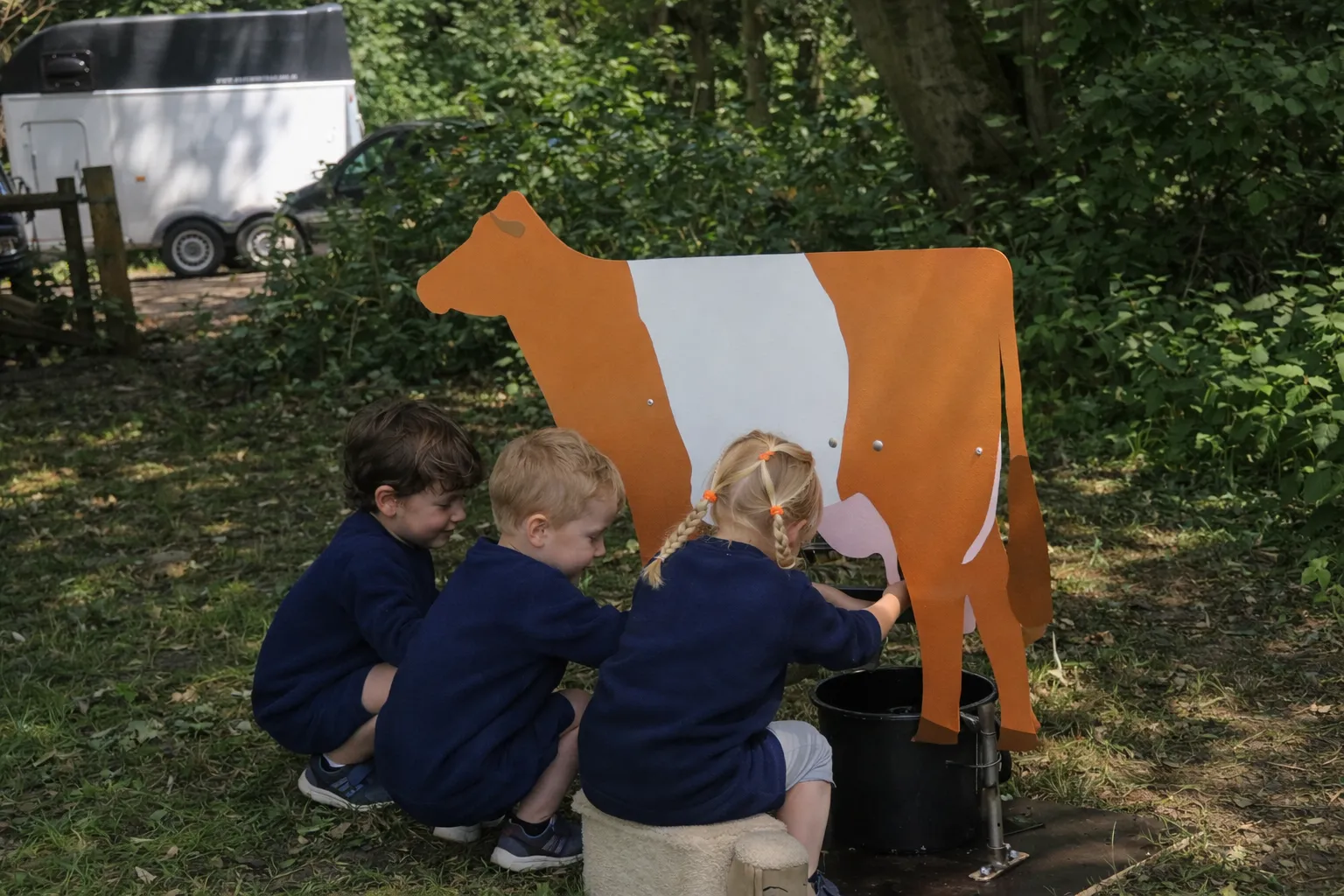 Kinderen oefenen met een houten koe op de boerderij