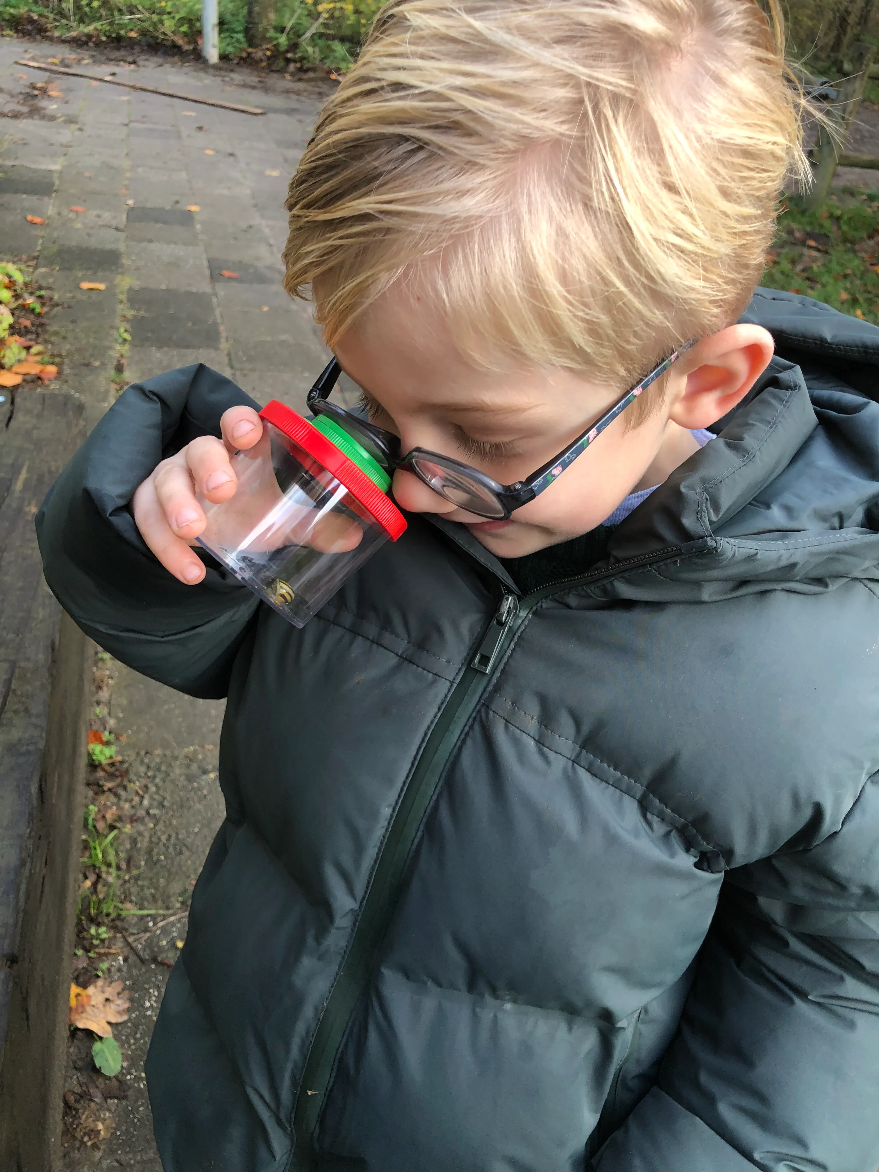 Kind bekijkt iets door een vergrootglas in de natuur