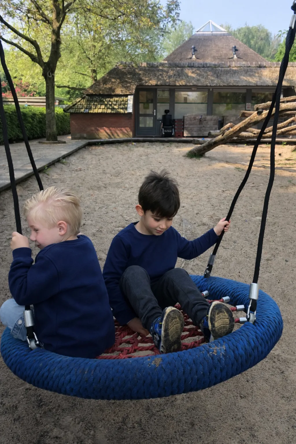 Twee kinderen spelen samen op een nestschommel